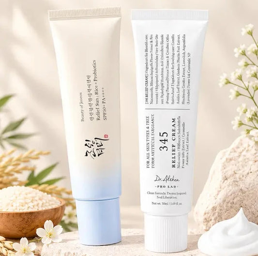 Two skincare tubes from thensmile 'The Korean Glow Duo' displayed on a stone surface with decorative flowers, grains, and a dollop of cream against a warm beige background.